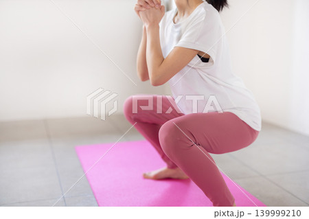 明るい室内で笑顔でスクワットをする日本人の若い女性 139999210