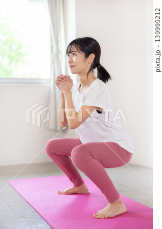 明るい室内で笑顔でスクワットをする日本人の若い女性 明るい室内で笑顔でスクワットをする日本人の若い女性 139999212