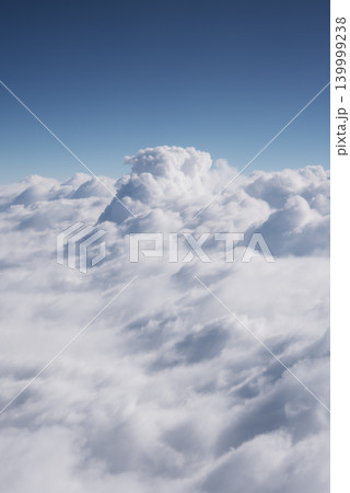 Blue sky and beautiful clouds. Aerial view of white fluffy clouds. View from an airplane on the way to vacation and holidays. Vertical wallpaper background. Copy space 139999238