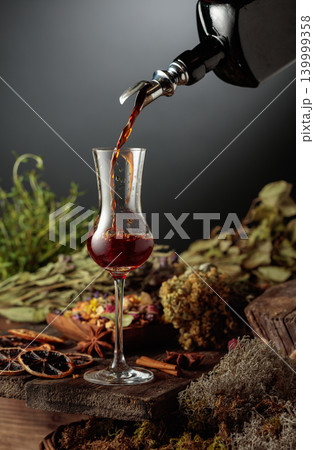 Herbal bitter liqueur is poured from a vintage bottle into a glass. Herbal bitter liqueur is poured from a vintage bottle into a glass. 139999358