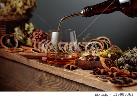 Herbal liquor is poured from a vintage bottle into a glass. Herbal liquor is poured from a vintage bottle into a glass. 139999362