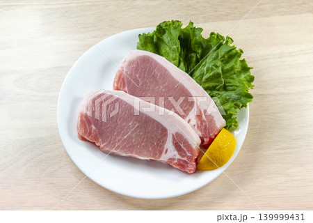 新鮮な豚肉のステーキ肉が白い皿にレモンと野菜とともに盛られた食材 新鮮な豚肉のステーキ肉が白い皿にレモンと野菜とともに盛られた食材 139999431