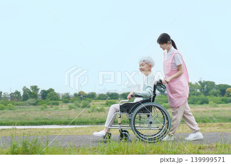 土手を散歩する車椅子に乗った日本人シニア女性と若い日本人介護士の女性 139999571