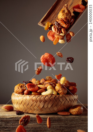 Mix of dried fruits is poured in a wicker bowl. 140000035