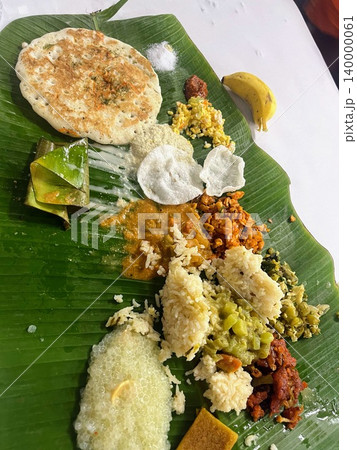 インドの結婚式でバナナの葉に盛られた伝統的なサディヤ料理とウッタパムや米が並ぶ祝祭のワンプレート インドの結婚式でバナナの葉に盛られた伝統的なサディヤ料理とウッタパムや米が並ぶ祝祭のワンプレート 140000061