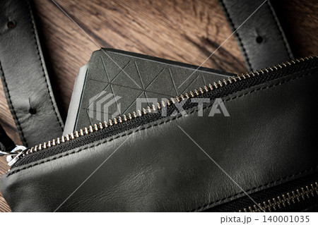Fashionable mens bag, men purse, wallet men's casual outfits with leather accessories, brown bag on wooden board background Fashionable mens bag, men purse, wallet men's casual outfits with leather accessories, brown bag on wooden board background 140001035