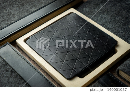 Handmade black wallet made of genuine leather on a wooden background. Close-up, top view. Handmade black wallet made of genuine leather on a wooden background. Close-up, top view. 140001087