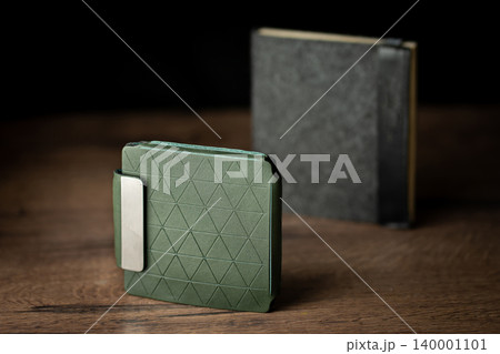 Handmade green wallet made of genuine leather on a wooden background. Close-up, top view. Handmade green wallet made of genuine leather on a wooden background. Close-up, top view. 140001101