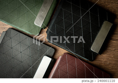 Handmade black wallet made of genuine leather on a wooden background. Close-up, top view. Handmade black wallet made of genuine leather on a wooden background. Close-up, top view. 140001110