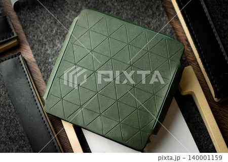 Handmade green wallet made of genuine leather on a wooden background. Close-up, top view. Handmade green wallet made of genuine leather on a wooden background. Close-up, top view. 140001159