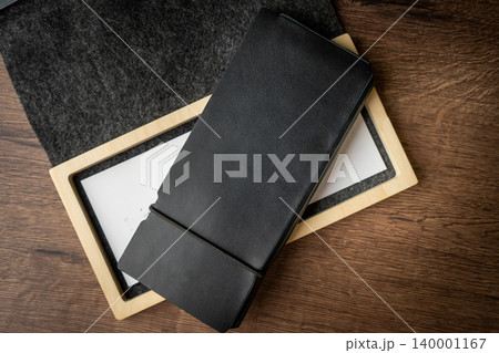 Handmade black wallet made of genuine leather on a wooden background. Close-up, top view. Handmade black wallet made of genuine leather on a wooden background. Close-up, top view. 140001167