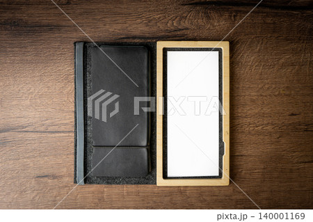 Handmade black wallet made of genuine leather on a wooden background. Close-up, top view. 140001169
