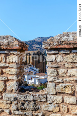 View of the town of Ronda, Spain, through a loophole in an ancient stone wall. 140001834