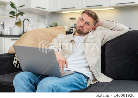 Young man works on laptop tired and demotivated deep sigh low energy struggles to focus long session Young man works on laptop tired and demotivated deep sigh low energy struggles to focus long session 140001920
