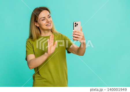 Woman waving hand while talking on smartphone video call smiling during happy online conversation Woman waving hand while talking on smartphone video call smiling during happy online conversation 140001949