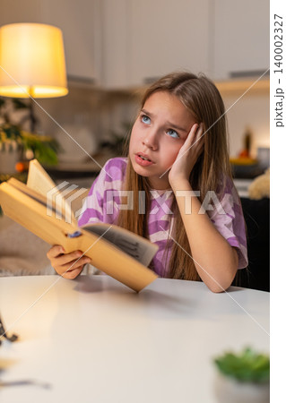 Teenager girl sad reading textbook does not understand task holds head worried sigh frustrated tired 140002327