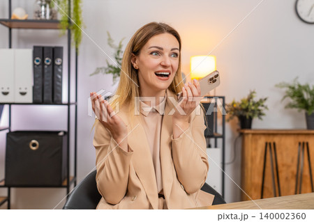 Businesswoman takes smartphone call with good news on speaker laughs thanks caller happy voice Businesswoman takes smartphone call with good news on speaker laughs thanks caller happy voice 140002360