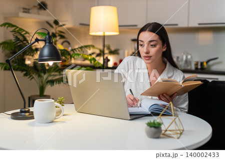Young woman study on laptop takes notes watches tutorial solves test prepares exams focused evening Young woman study on laptop takes notes watches tutorial solves test prepares exams focused evening 140002433