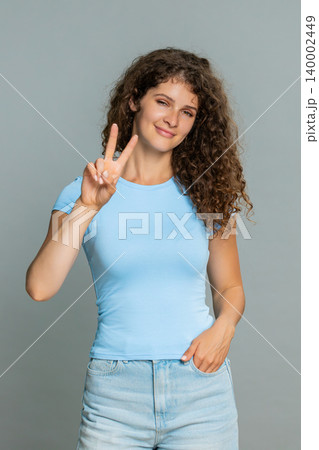 Young happy woman showing peace victory V hand sign cheerful positive joyful optimistic expression Young happy woman showing peace victory V hand sign cheerful positive joyful optimistic expression 140002449