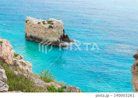 Dramatic rocky cliffs meet vibrant aquamarine waters in a tropical paradise 140003261