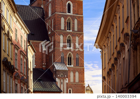 Historic European narrow street with old brick church tower and ornate buildings 140003394