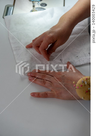 Vertical close up of woman working with fabric and sewing pins in atelier 140003429