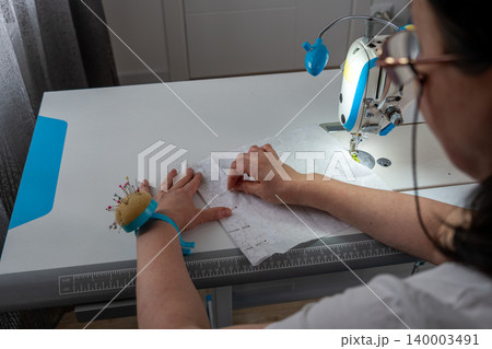 Woman working with fabric and sewing pins in atelier Woman working with fabric and sewing pins in atelier 140003491