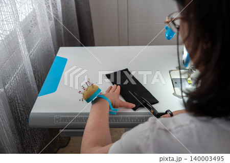 Woman cutting marked fabric during tailoring process Woman cutting marked fabric during tailoring process 140003495