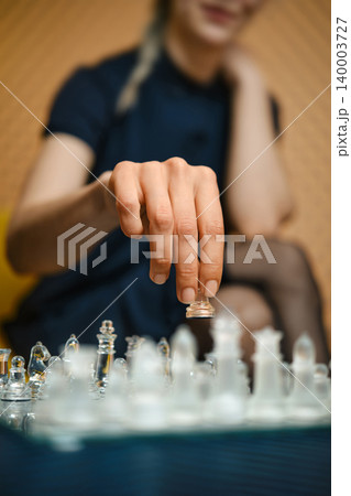 Player makes a move on glass chessboard during game in indoor setting in the afternoon 140003727