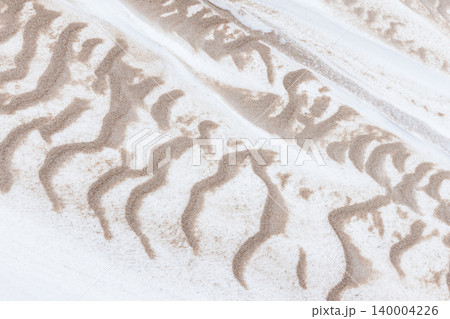 Organic, abstract patterns of sand swept across white snow Organic, abstract patterns of sand swept across white snow 140004226