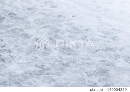 Snow-covered icy ground with packed snow and footprints 140004239