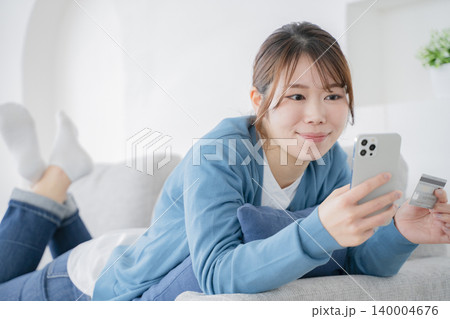 ソファでくつろぎながらスマホを見る女性 ソファでくつろぎながらスマホを見る女性 140004676