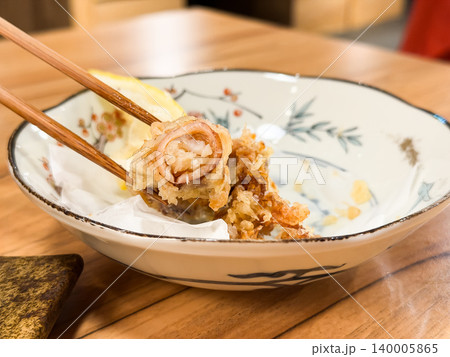 イカフライ。小さいイカを丸ごと揚げた料理。レモンのくし切りを添えて。箸で持って断面を見せているところ イカフライ。小さいイカを丸ごと揚げた料理。レモンのくし切りを添えて。箸で持って断面を見せているところ 140005865