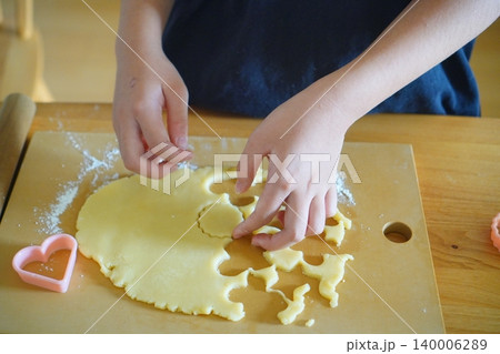 子供がクッキー生地を型抜きする手元お菓子作り家庭料理体験写真 140006289