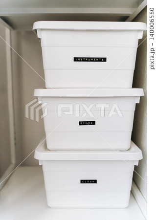 Minimal white storage boxes stacked on shelf with labels for organization Minimal white storage boxes stacked on shelf with labels for organization 140006580