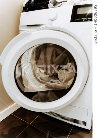 Open washing machine with a load of clothes 140006595