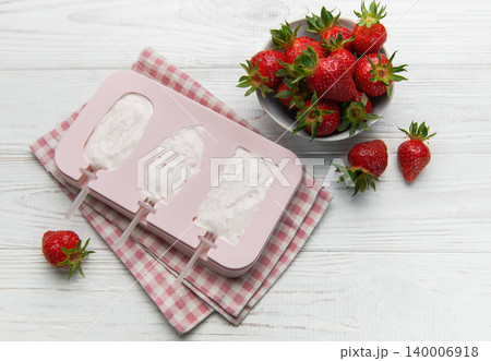 Making homemade strawberry ice cream popsicles in silicone mold 140006918
