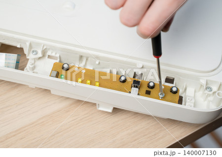 Close-Up Of Hand Using Screwdriver To Repair Electronic Circuit Board Inside All in one Printer Close-Up Of Hand Using Screwdriver To Repair Electronic Circuit Board Inside All in one Printer 140007130
