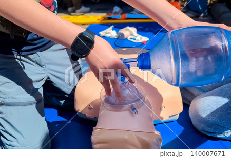 Children learning first aid during cpr training on a medical mannequin. Kids practicing artificial ventilation using an ambu bag resuscitator. Children learning first aid during cpr training on a medical mannequin. Kids practicing artificial ventilation using an ambu bag resuscitator. 140007671