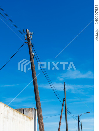 Wooden Utility Poles with Power Lines Against Blue Sky 140007925