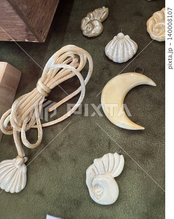 Carved shell ornaments and rope displayed on textured olive green background Carved shell ornaments and rope displayed on textured olive green background 140008107