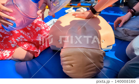 First aid training with CPR mannequin. Medical students practicing cardiopulmonary resuscitation and using an Ambu bag mask for artificial ventilation during a first aid seminar. First aid training with CPR mannequin. Medical students practicing cardiopulmonary resuscitation and using an Ambu bag mask for artificial ventilation during a first aid seminar. 140008160