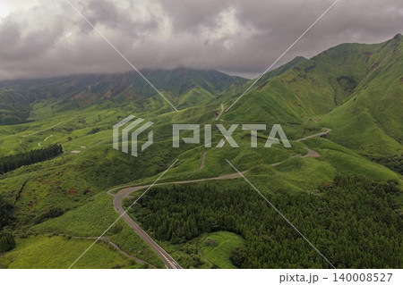 熊本県南阿蘇の緑の山岳地帯を縫うワインディングロードの空撮写真 140008527