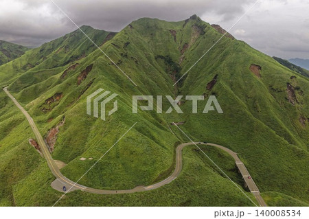 熊本県南阿蘇の緑の山肌を縫う曲がりくねった山岳道路の空撮写真 熊本県南阿蘇の緑の山肌を縫う曲がりくねった山岳道路の空撮写真 140008534