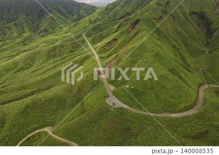 熊本県南阿蘇の緑の山腹を縫う蛇行山岳道路の空撮写真 140008535