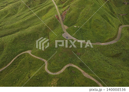 熊本県南阿蘇の緑の草原を縫う山岳道路を俯瞰した空撮写真 熊本県南阿蘇の緑の草原を縫う山岳道路を俯瞰した空撮写真 140008536