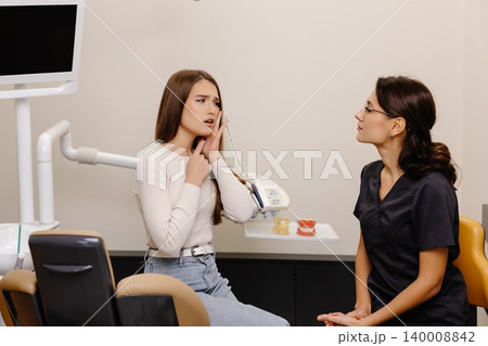 Dentist specialist talking with patient in dentistry office. Young woman dentist explaining teeth treatment at consultation in modern clinic Dentist specialist talking with patient in dentistry office. Young woman dentist explaining teeth treatment at consultation in modern clinic 140008842