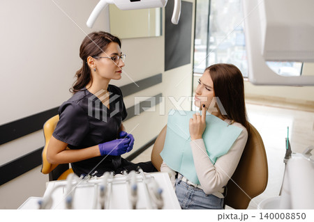 Young woman experiencing pain and anxiety while having a dental procedure performed on her 140008850