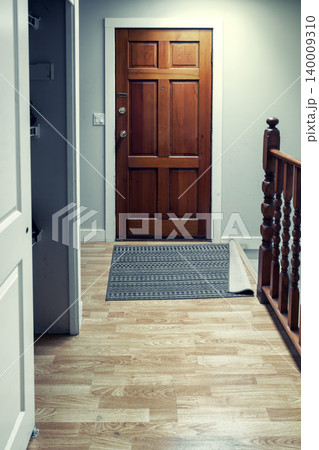 Wooden front door with doormat in home entrance hallway 140009310