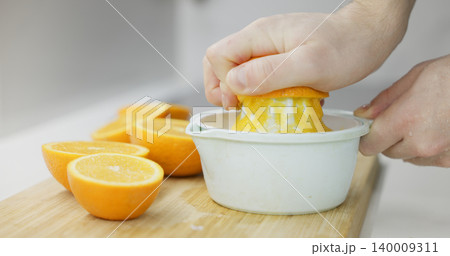 Hands extracting fresh orange juice for a healthy beverage 140009311
